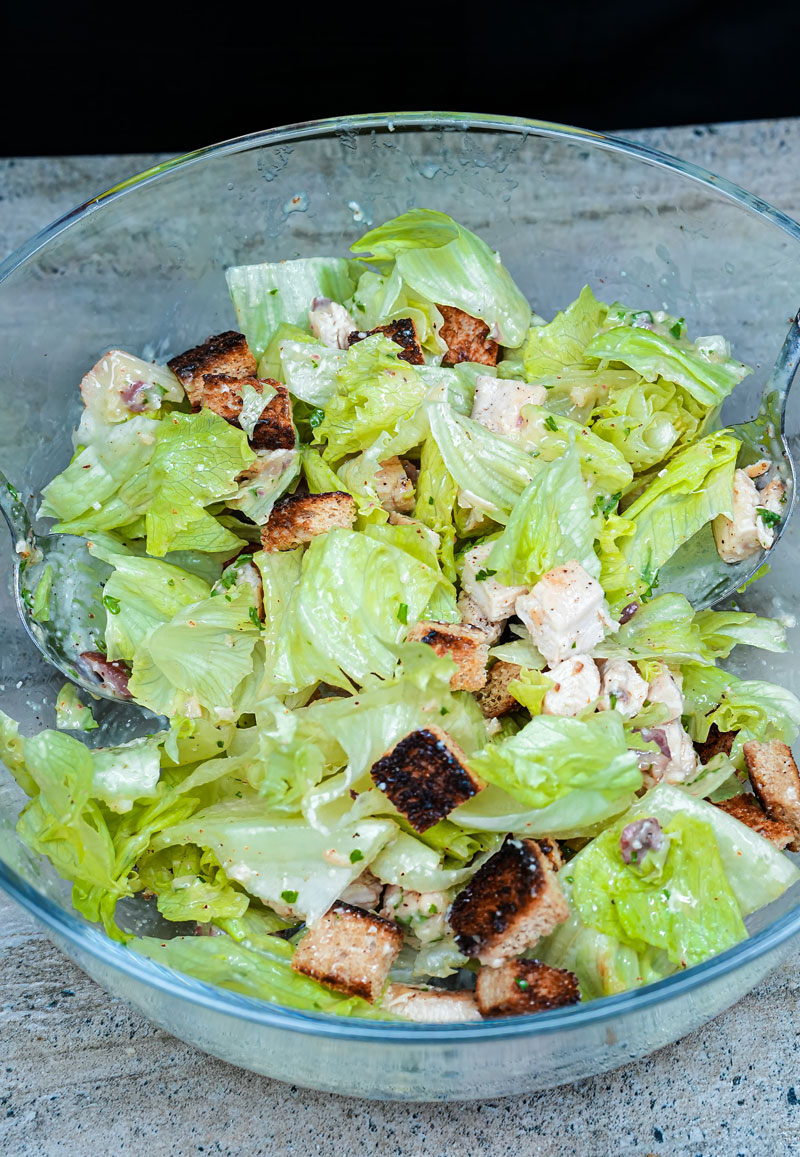 Mixed Chicken Caesar Salad in a glass bowl with grilled chicken and crunchy croutons.