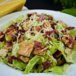 Freshly prepared Chicken Caesar Salad garnished with crispy croutons and shredded Parmesan.