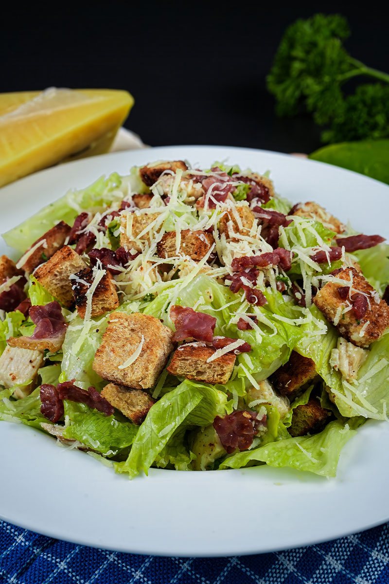 Freshly prepared Chicken Caesar Salad garnished with crispy croutons and shredded Parmesan.