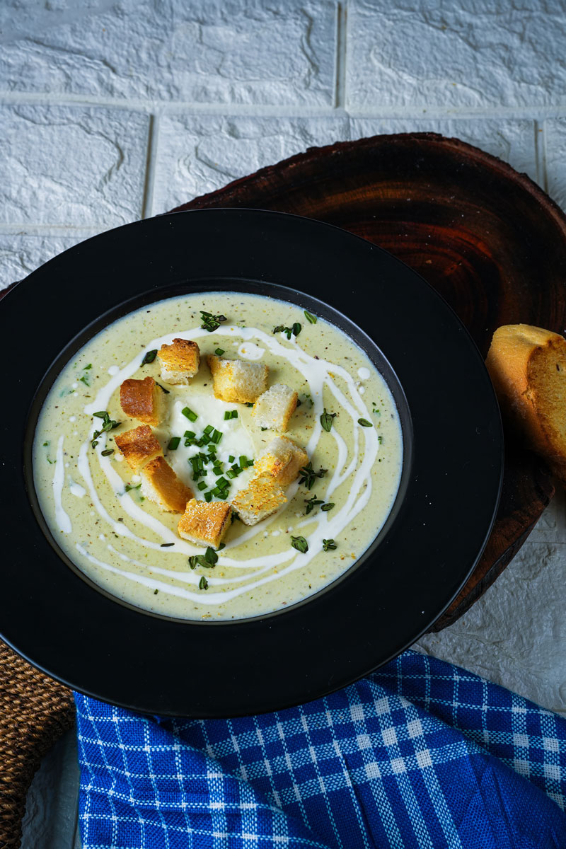 Creamy leek potato soup with croutons and herbs, served alongside toasted bread.