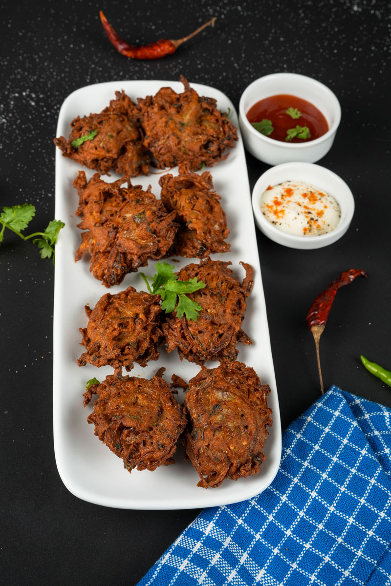 Crispy onion fritters on a white plate with dipping sauces