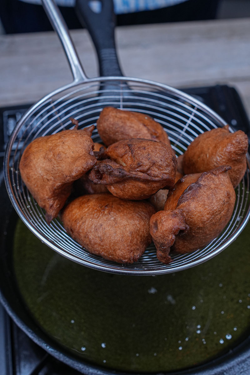 Freshly fried banana fritters in a strainer over oil