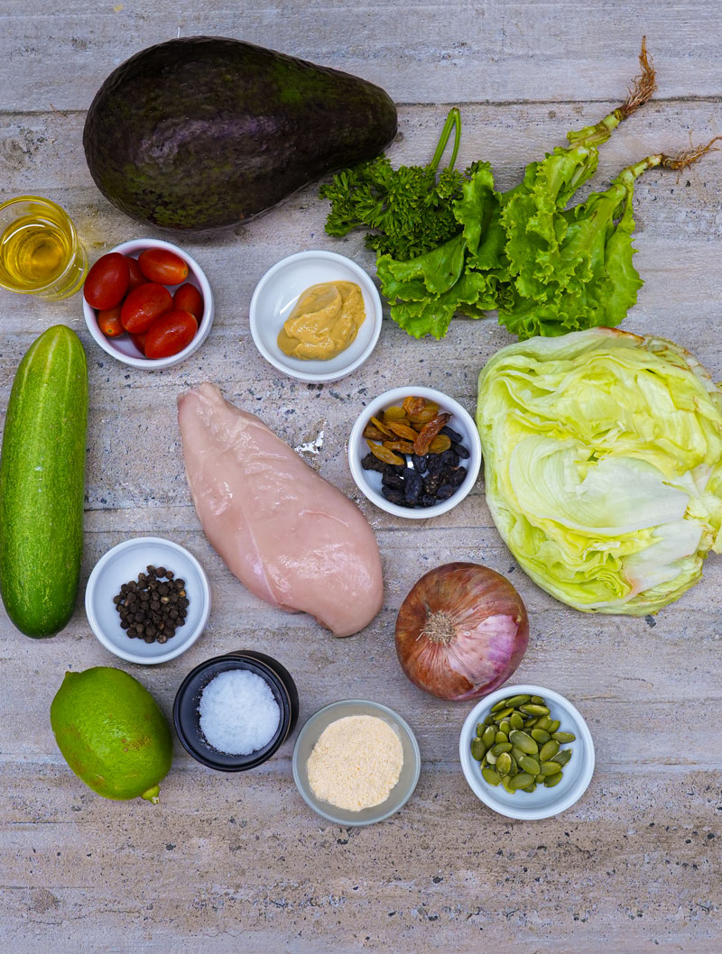 Ingredients for grilled chicken avocado salad, including avocado, chicken, and vegetables.