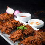 Close-up of onion fritters with chutney and yogurt dip