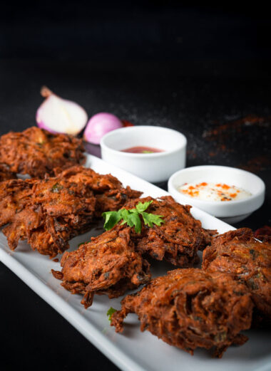 Close-up of onion fritters with chutney and yogurt dip