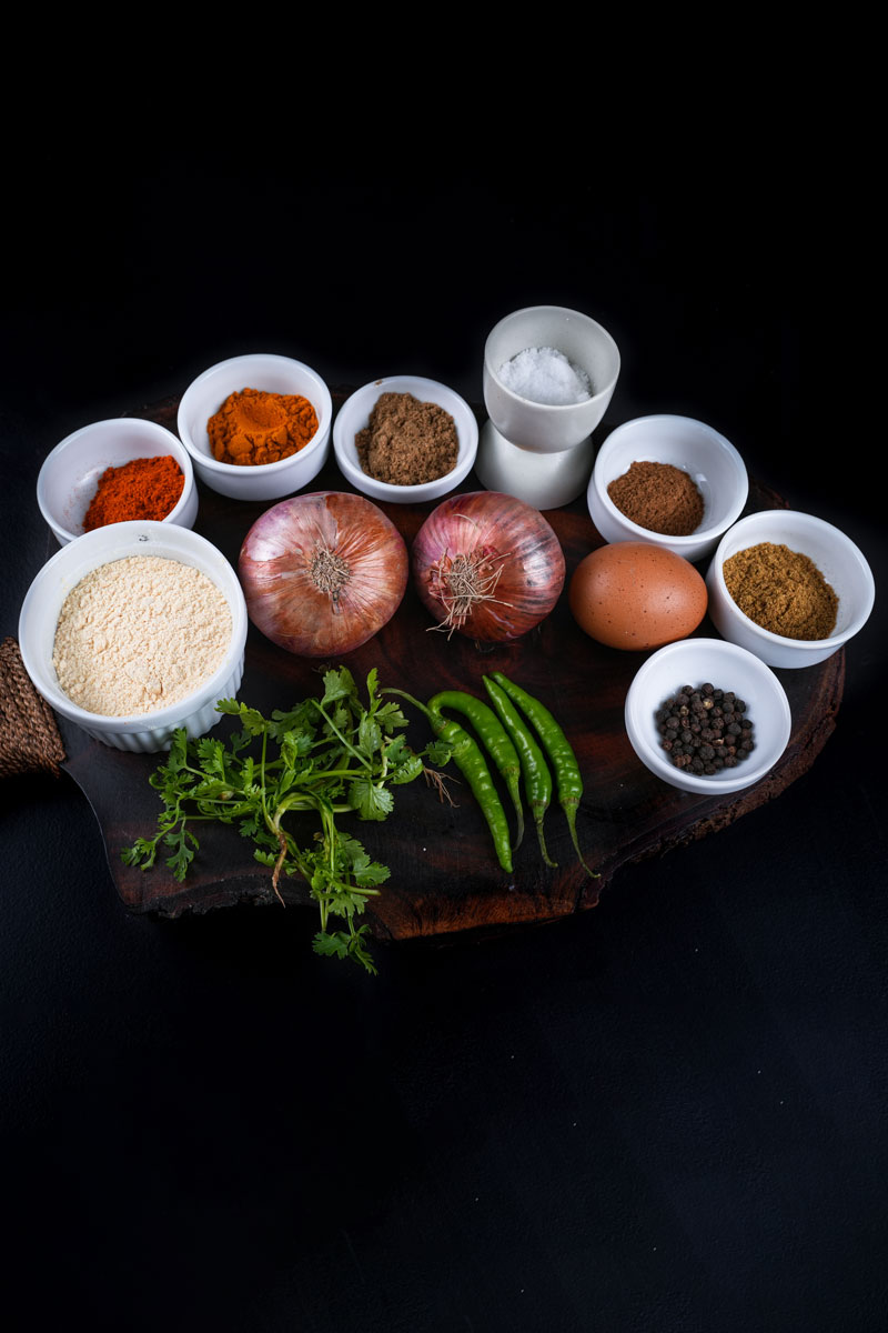 Assorted ingredients for making onion fritters on a dark background