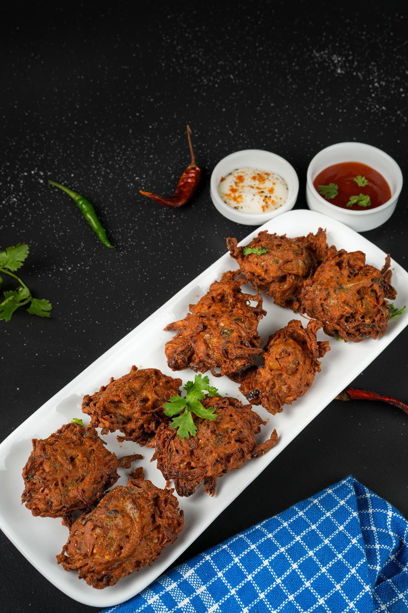 Crispy onion fritters with yogurt and tomato dips on a white platter