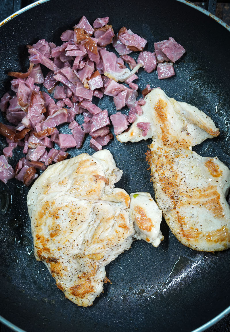 Grilled chicken and chopped bacon cooking in a skillet for Chicken Caesar Salad.