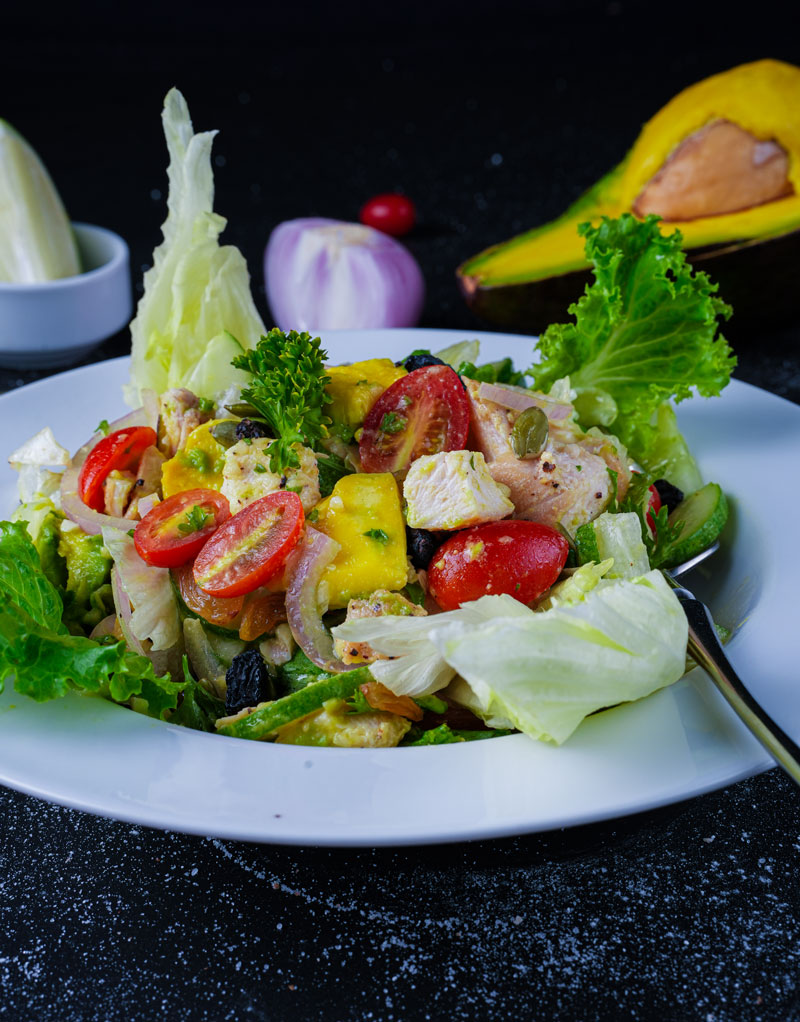 Close-up of grilled chicken avocado salad with vibrant vegetables.