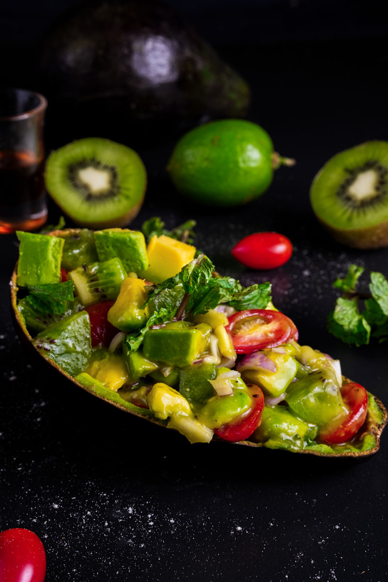 Close-up of avocado kiwi salad with fresh ingredients like lime and mint.