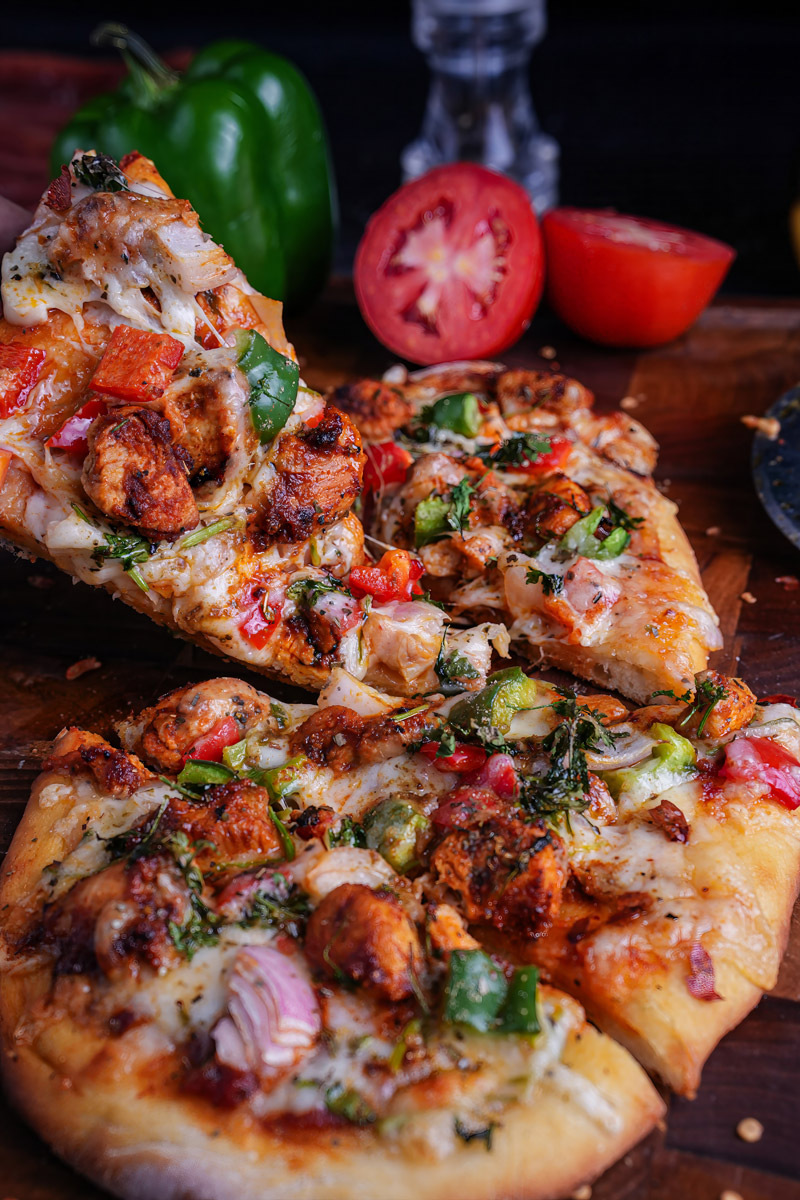 Sliced Tandoori Paneer Pizza Naan with melted cheese and vibrant toppings.