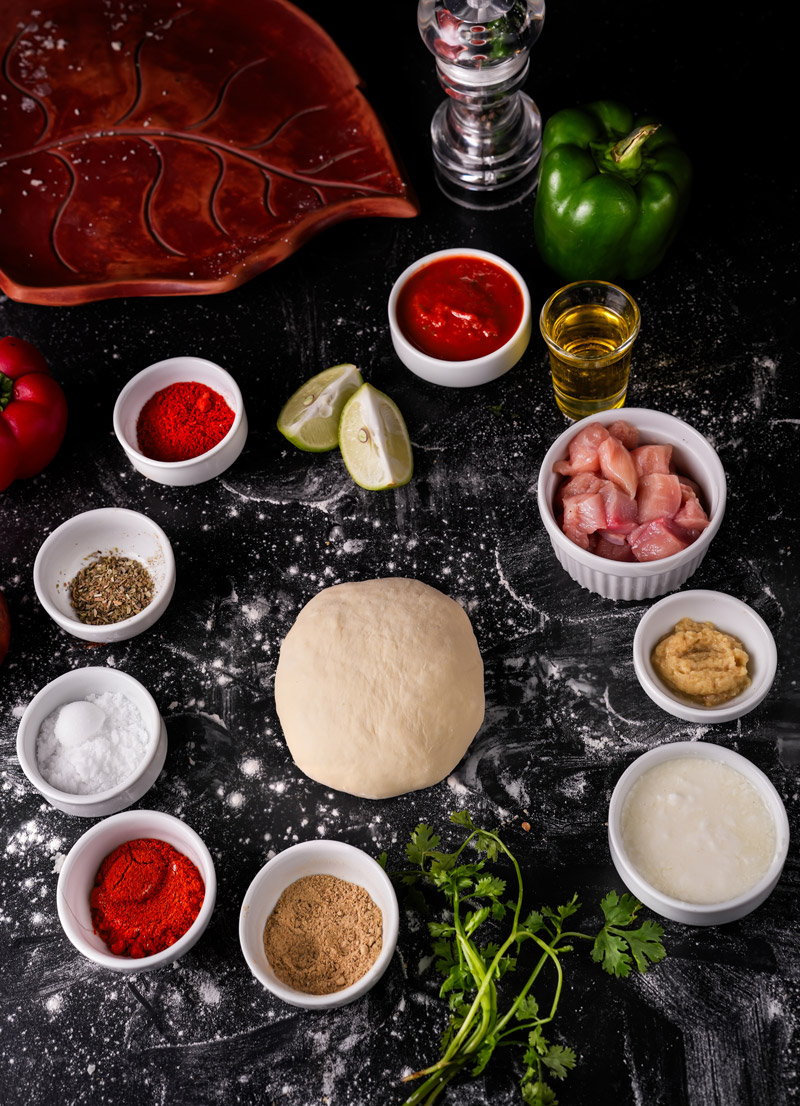 Ingredients for Tandoori Paneer Pizza Naan, including dough, spices, and fresh vegetables.