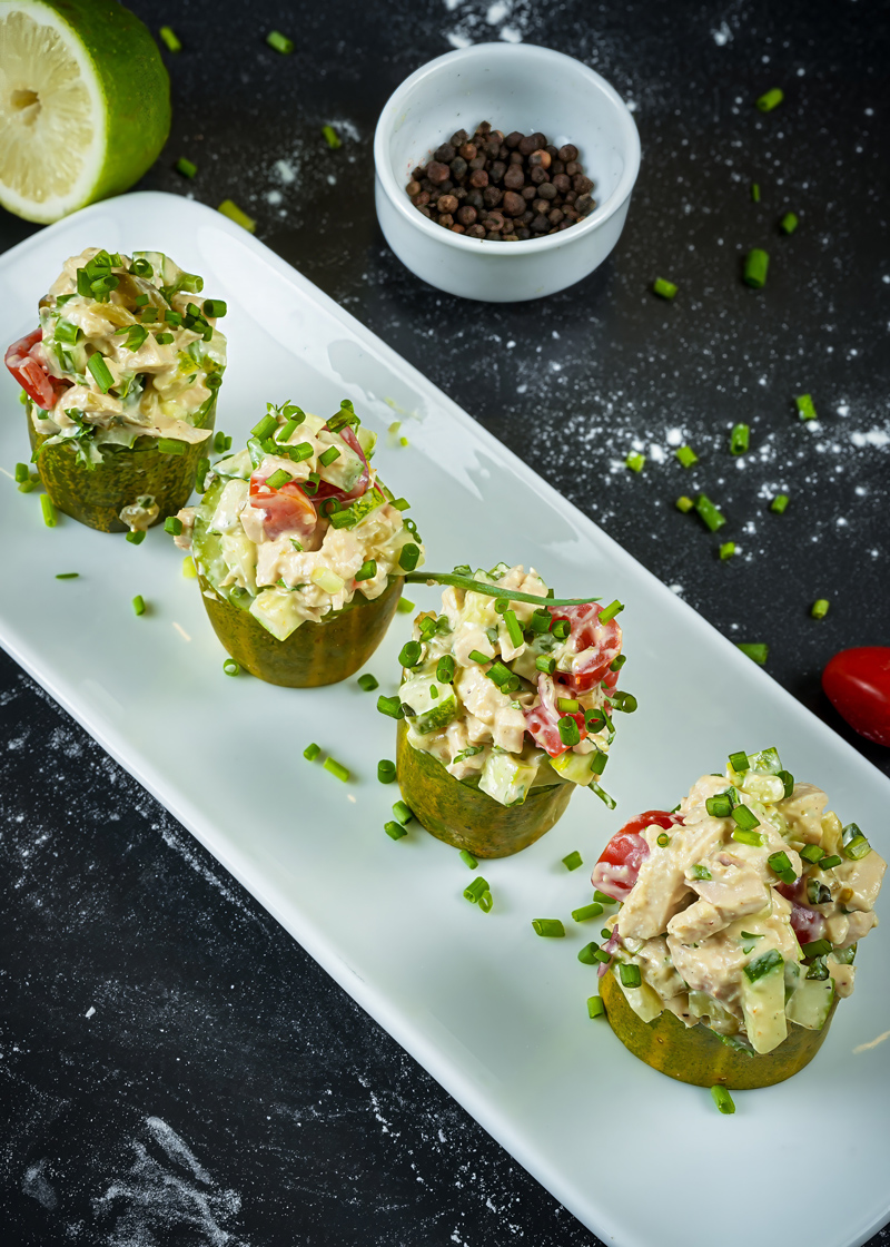 Top-down view of chicken salad garnished with herbs on a clean black background.