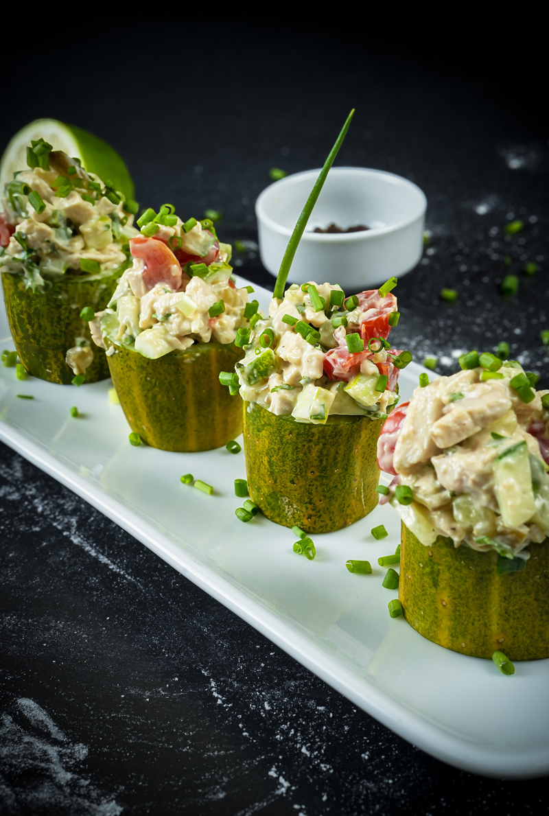 Chicken salad served in cucumber cups garnished with fresh chives