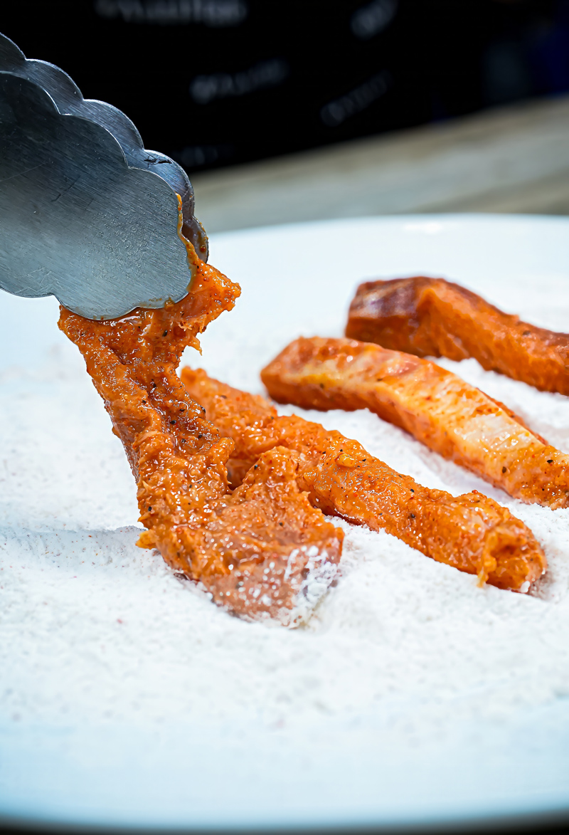 Marinated fish fillets being coated with flour for frying.