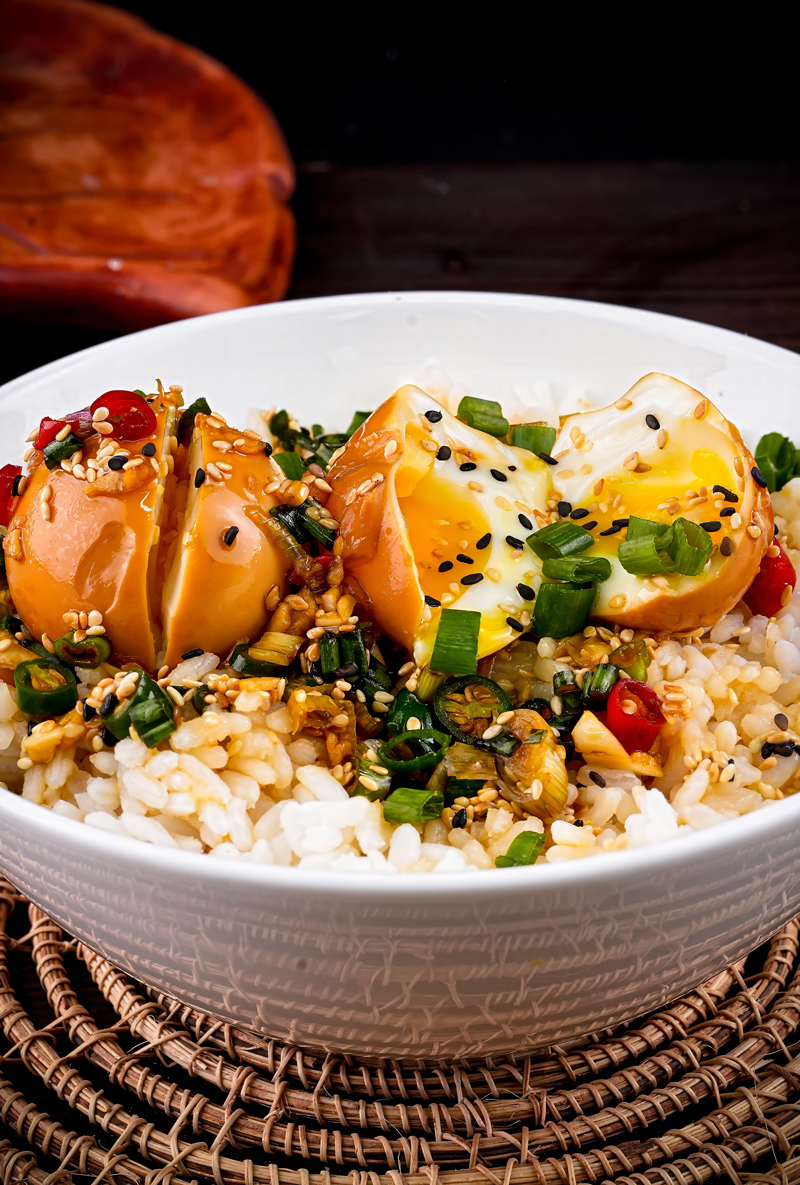 Korean-style marinated eggs sliced open on a bowl of rice, showcasing a soft yolk.