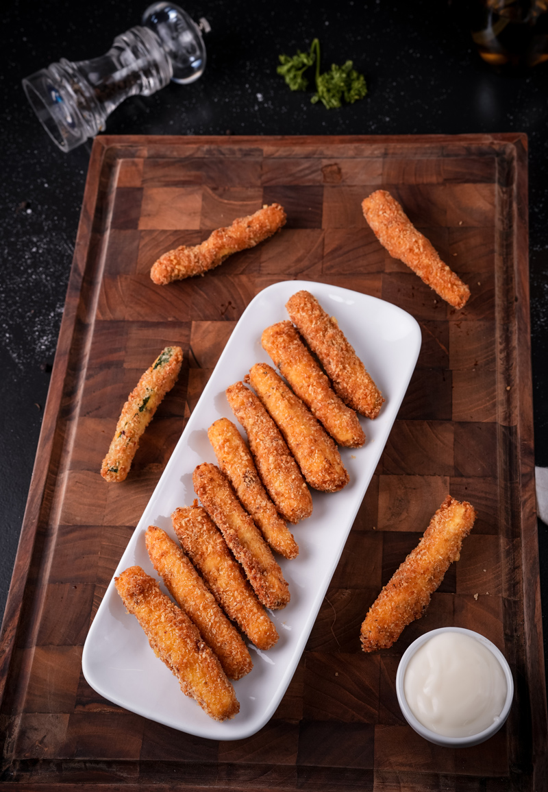 Zucchini sticks being deep-fried in a pan of oil.