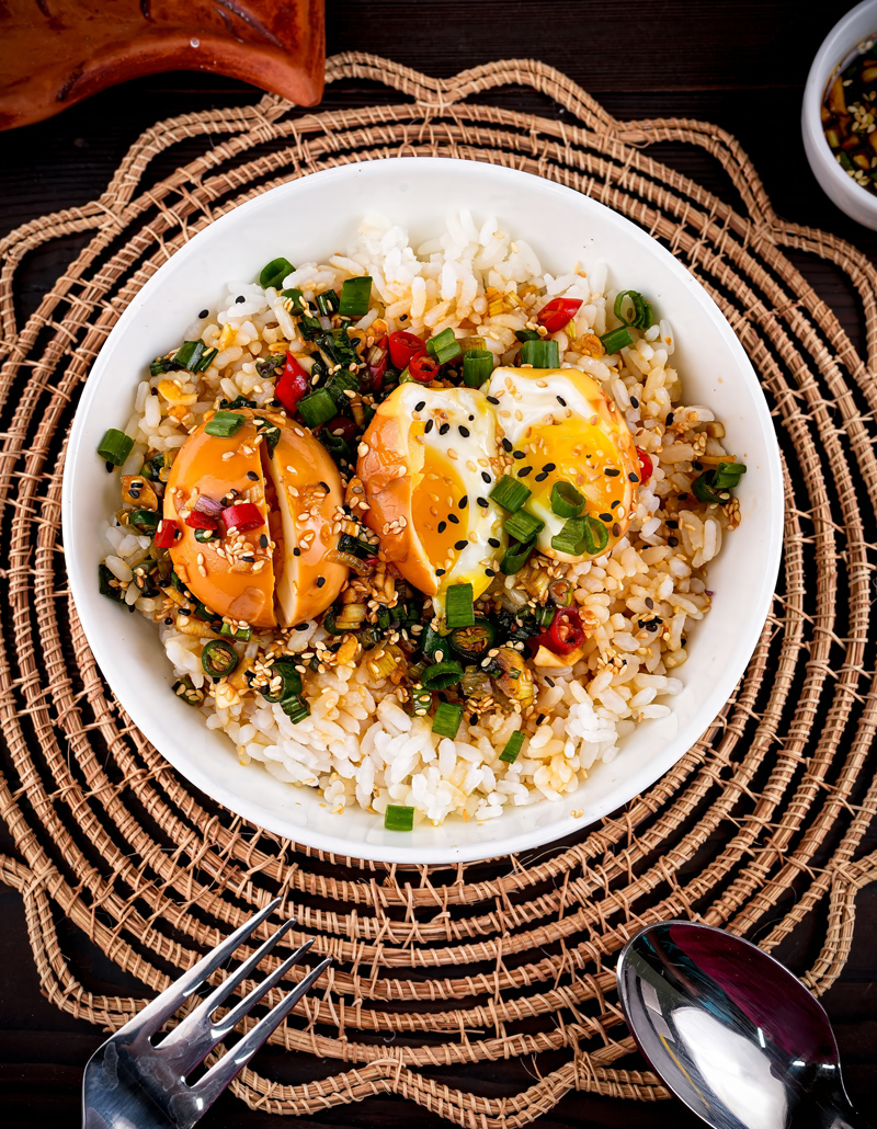 Close-up of Mayak Eggs served over a bowl of rice, garnished with sesame seeds and scallions.