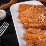 Deep-fried zucchini garnished with cheese and parsley.