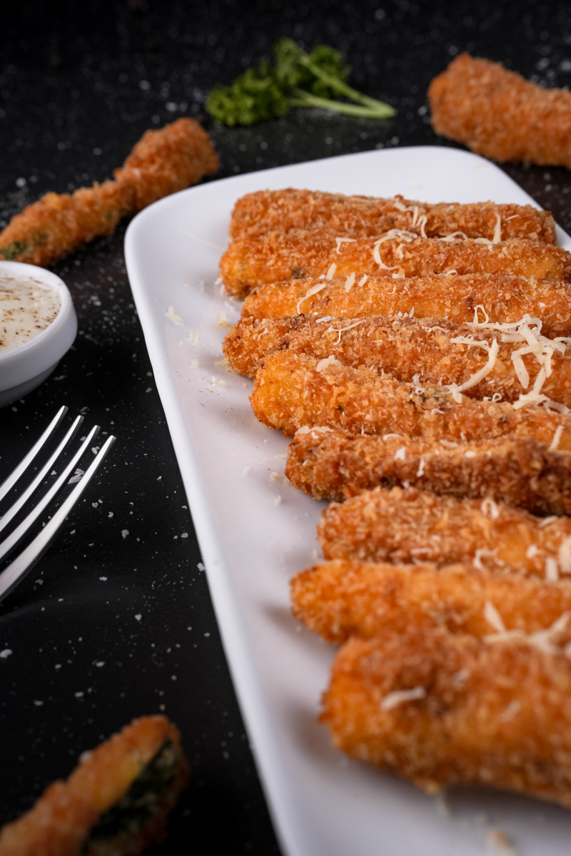 Deep-fried zucchini garnished with cheese and parsley.