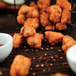 Fish Popcorn served with sauces on a wooden table.