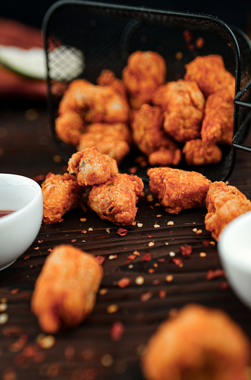 Fish Popcorn served with sauces on a wooden table.