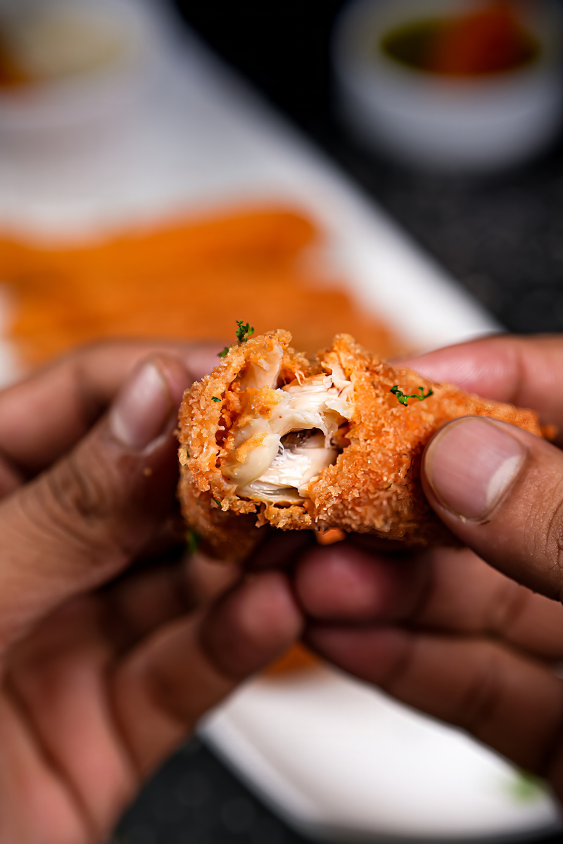 Hands holding a fish stick with a bite revealing flaky fish inside.