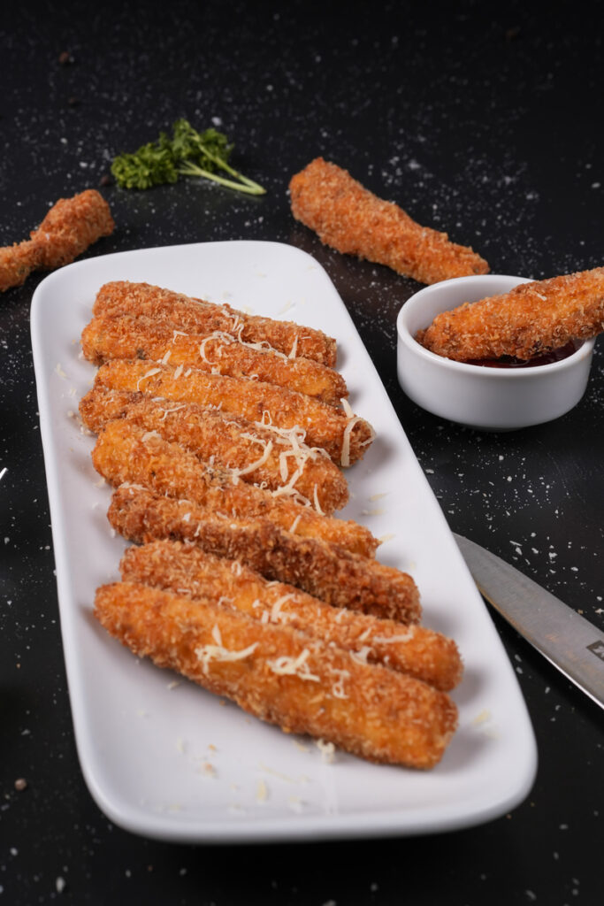 A plate of golden fried zucchini served with dipping sauces.