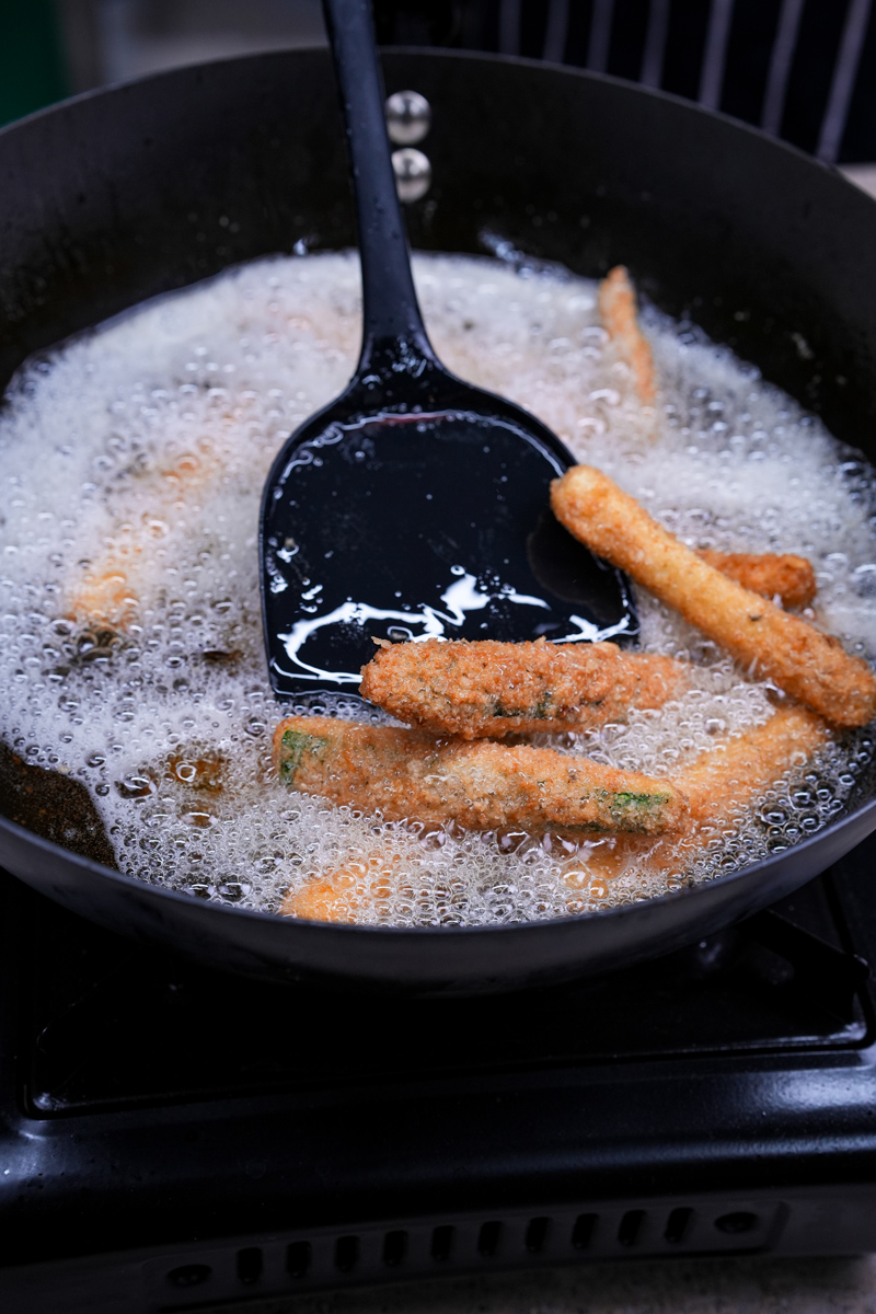 Perfectly arranged breadcrumbed zucchini sticks before frying.