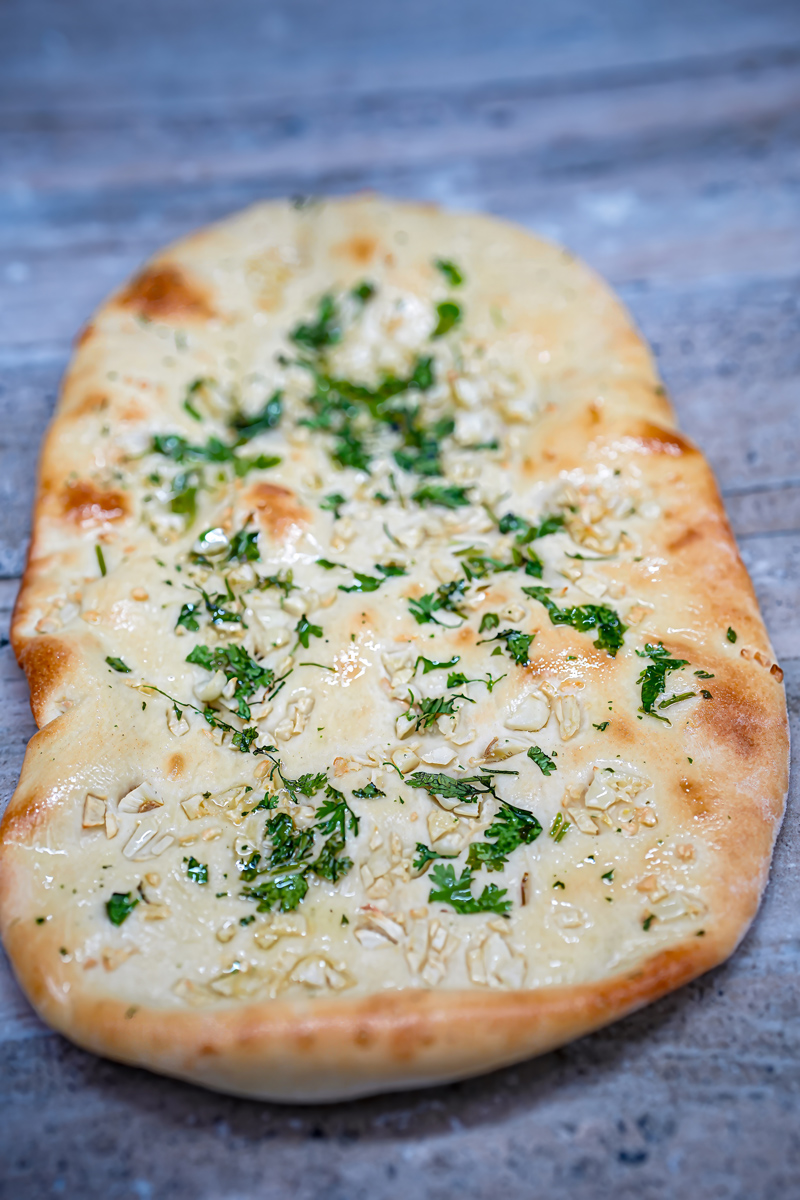 Freshly baked garlic naan with herbs and butter.