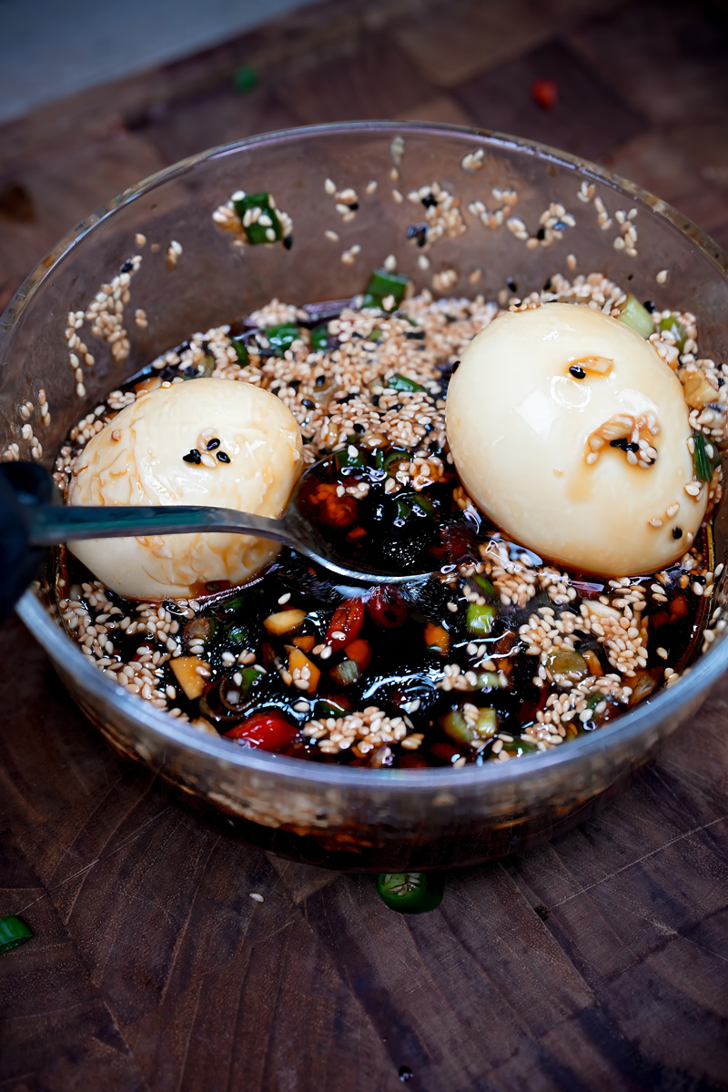 Korean Mayak Eggs marinated in a soy-based sauce with sesame seeds and chili peppers.