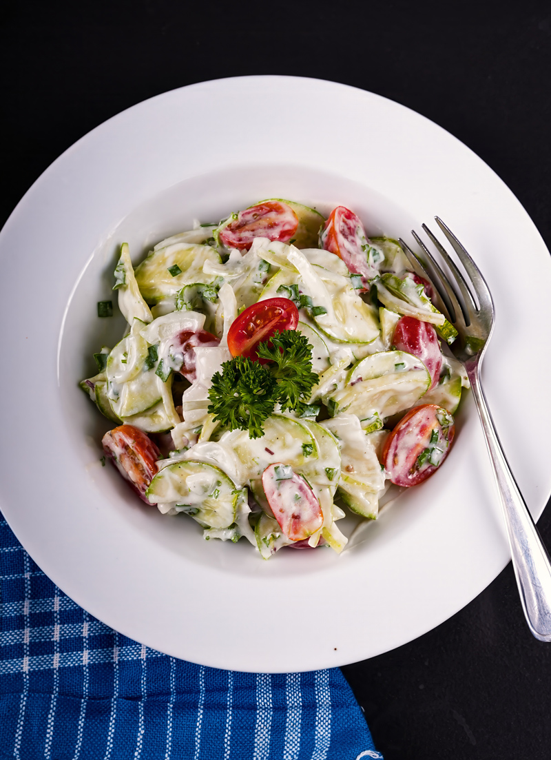 Close-up of creamy cucumber tomato salad with cherry tomatoes and cucumber slices.