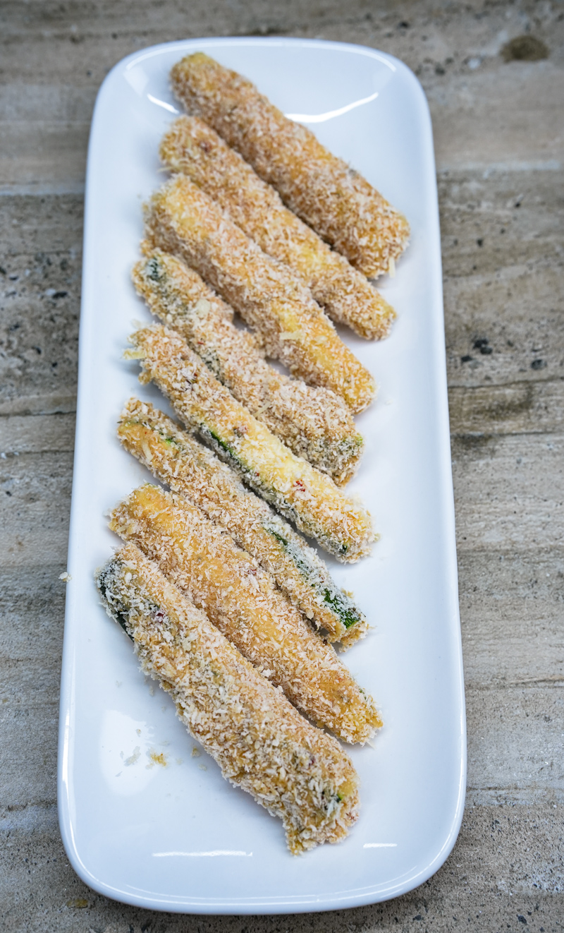 Breadcrumb-coated zucchini sticks on a plate.