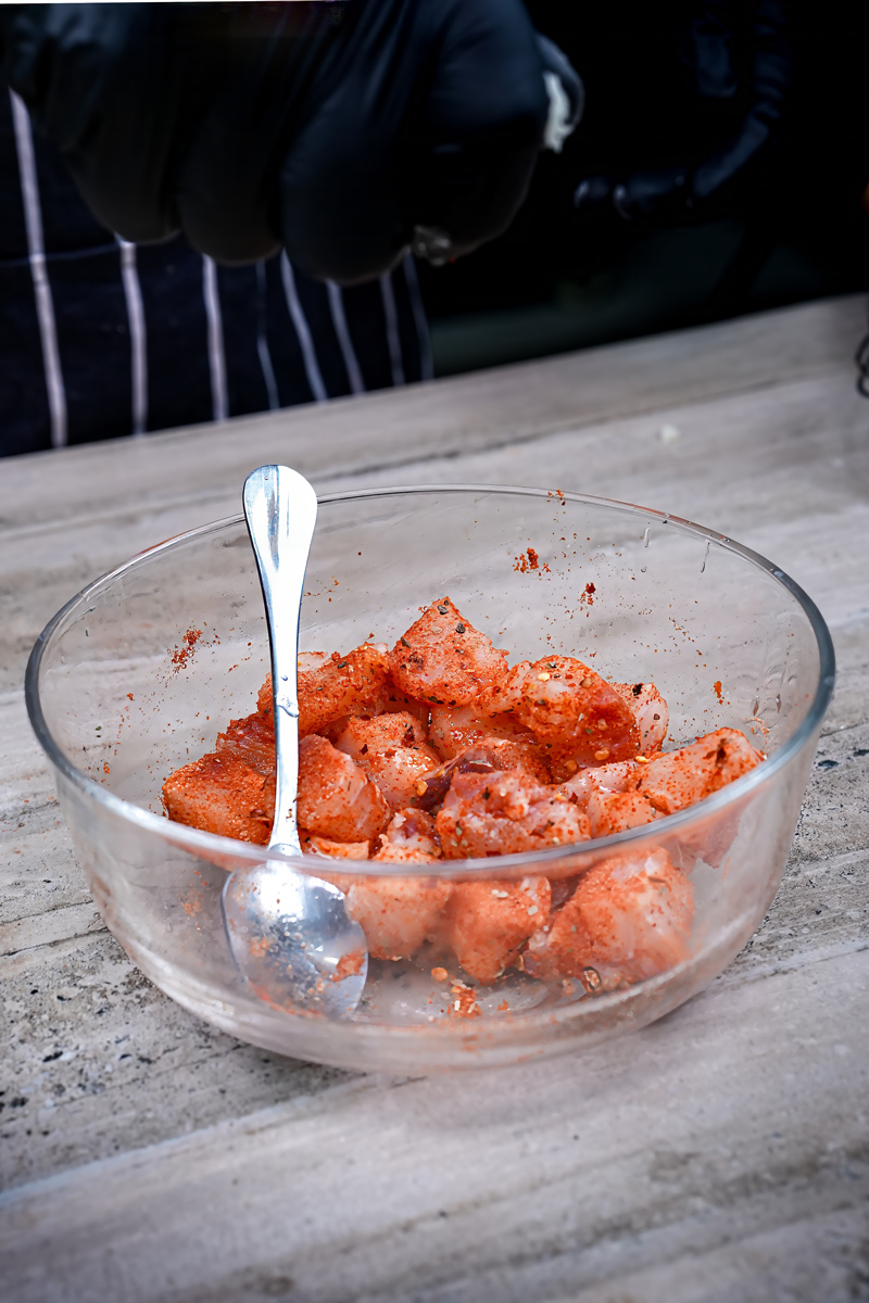 Fish pieces marinated with spices in a glass bowl.