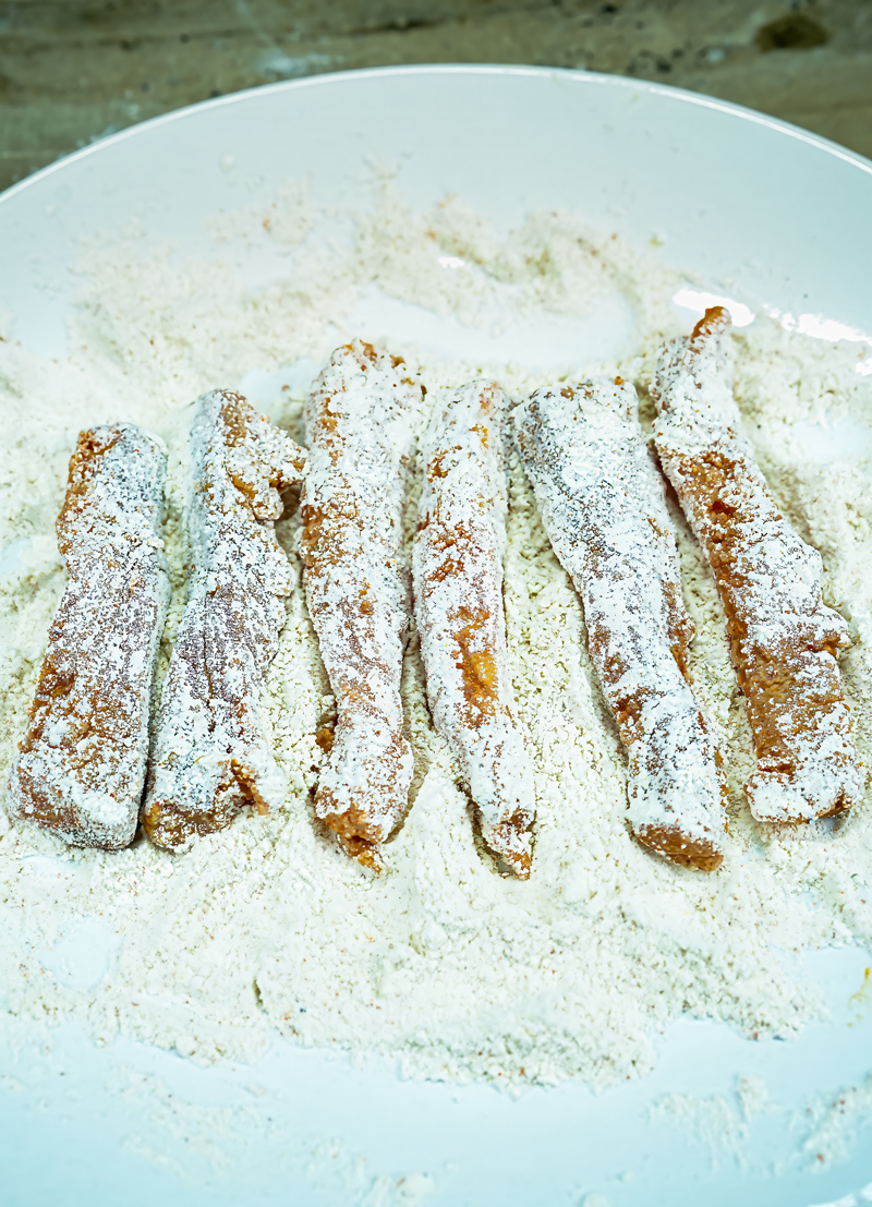 Fish sticks coated in flour and breadcrumbs, ready for frying.