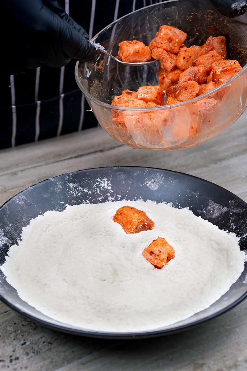 Marinated fish pieces being coated with flour for Fish Popcorn.