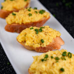 Perfectly arranged scrambled eggs on toast with a dark, elegant backdrop.