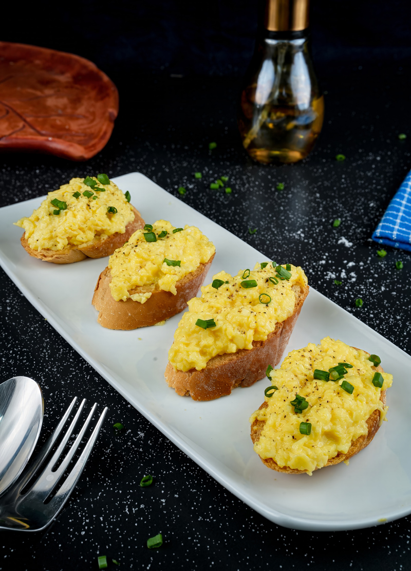 Close-up of creamy scrambled eggs on toast with a sprinkle of pepper.