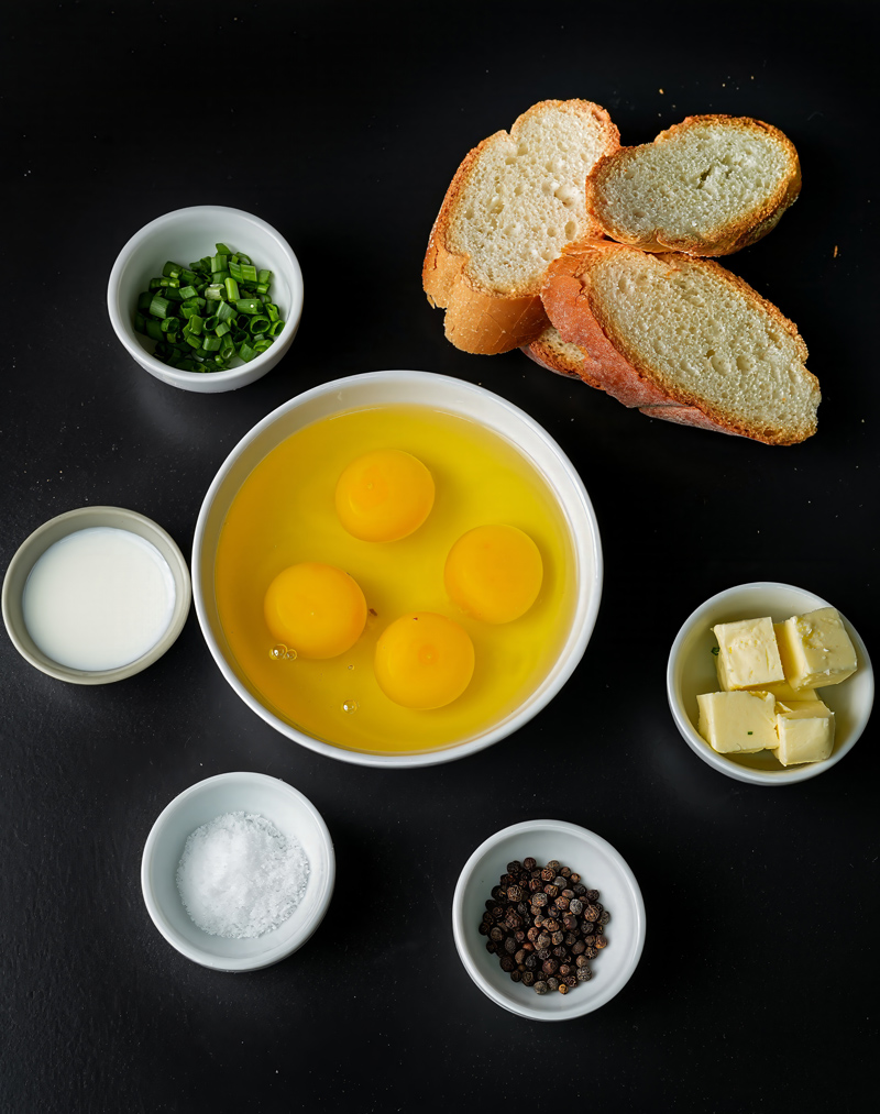 Ingredients for scrambled eggs and toast, including eggs, bread, butter, and seasoning.