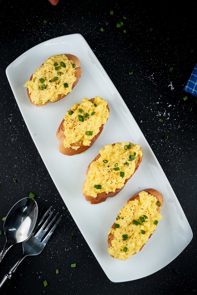 Scrambled eggs on toast garnished with chopped green onions.