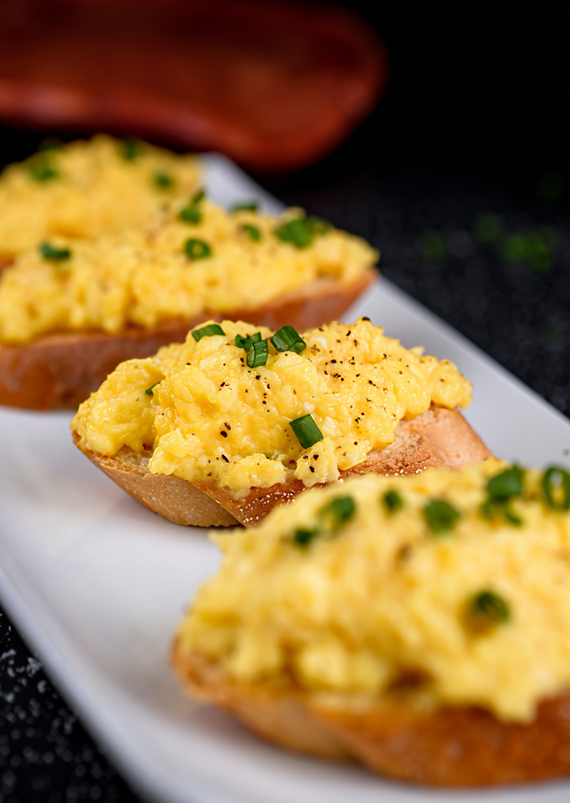 Side view of scrambled eggs toast with a minimalistic black background.