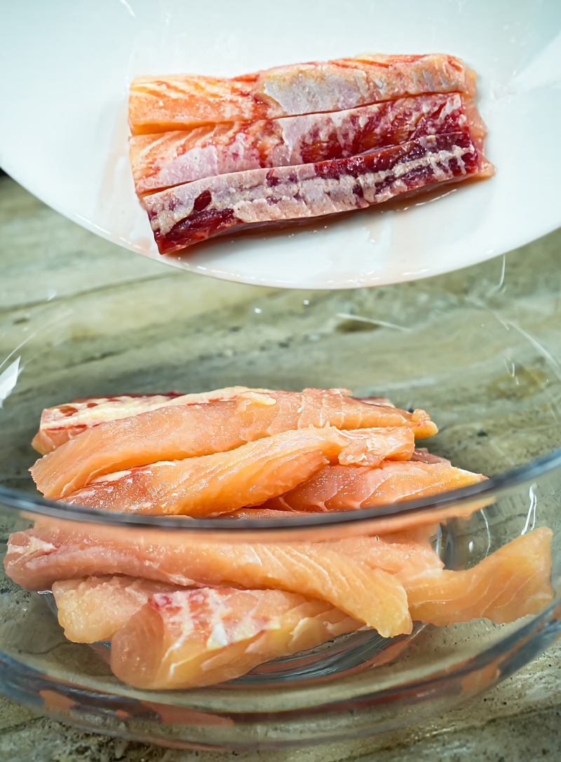 Raw fish fillets placed in a glass bowl for marination.