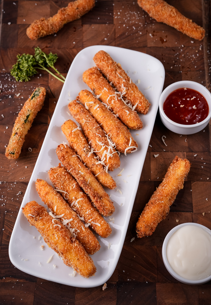 Golden, crispy fried zucchini sticks served on a plate.