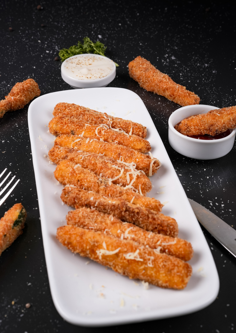 Close-up of fried zucchini sticks with shredded cheese topping.