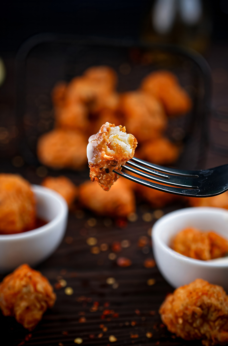 Close-up of a bite of crispy Fish Popcorn on a fork.