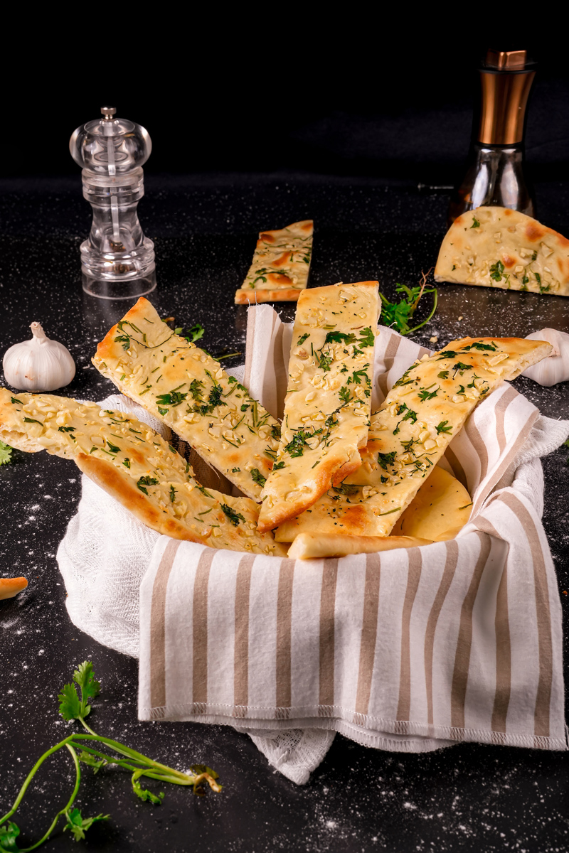 Rustic serving of homemade garlic naan slices.