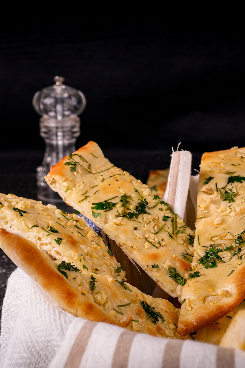 Brushing melted butter on garlic naan slices.