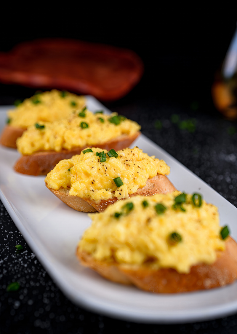 Close-up of buttery scrambled eggs toast with garnish for a breakfast recipe.