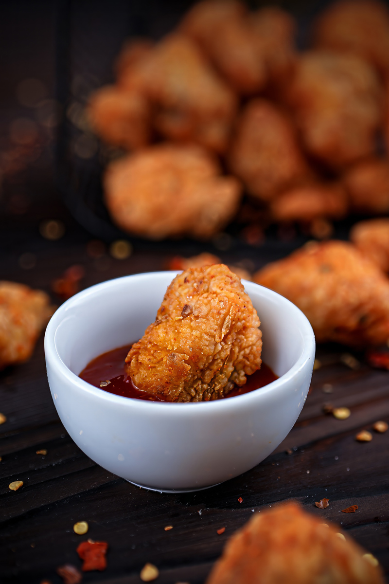 Close-up of Fish Popcorn dipped in tangy sauce.