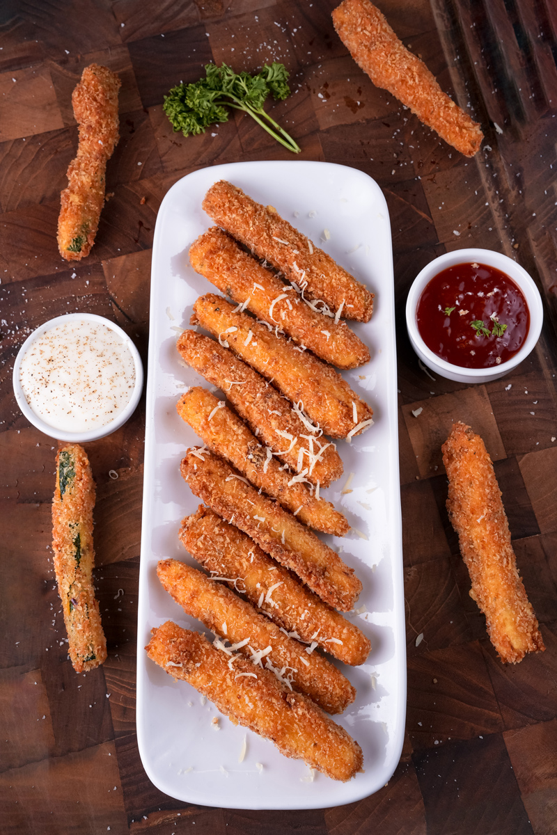 Fried zucchini sticks garnished with cheese and served with dipping sauces.